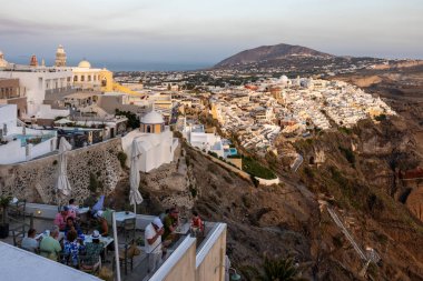Yunanistan 'ın Kiklad adasındaki Santorini Adası' nda beyazlatılmış Fira kasabası gün batımının ılık ışınlarıyla