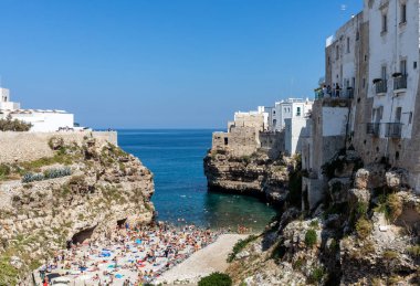 Polignano, İtalya - 17 Eylül 2019: İnsanlar Polignano a Mare, Adriyatik Denizi, Apulia, Bari ili, İtalya 'daki sevimli Lama Monachile plajında dinleniyor ve yüzüyorlar,