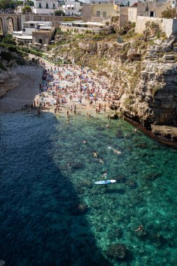 Polignano a Mare, İtalya - 17 Eylül 2019: İnsanlar Polignano a Mare, Adriyatik Denizi, Apulia, Bari ili, İtalya 'daki sevimli Lama Monachile plajında dinleniyor ve yüzüyorlar,