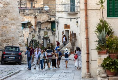 Matera, İtalya - 14 Eylül 2019: Matera şehrinin tarihi bir bölgesi olan Sassi di Matera 'daki Cobblestone caddesinde yürüyüş yapan turistler. Basilicata. İtalya