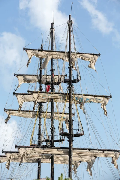 Masts and sails of huge sailing boat against the background of blue sky — Stock Photo, Image