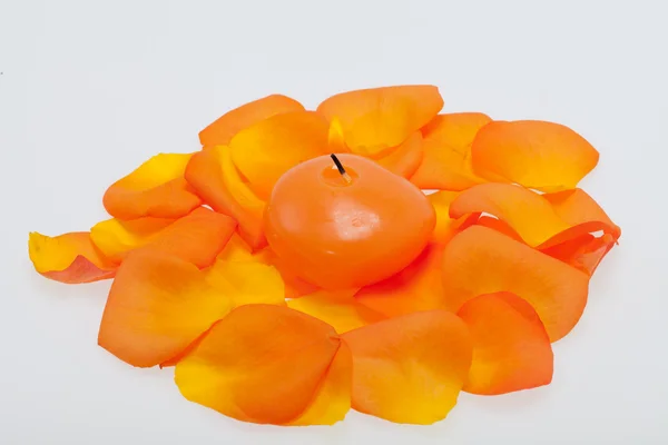 Verschüttete Blütenblätter der Orangenrose um die aromatische Kerze — Stockfoto