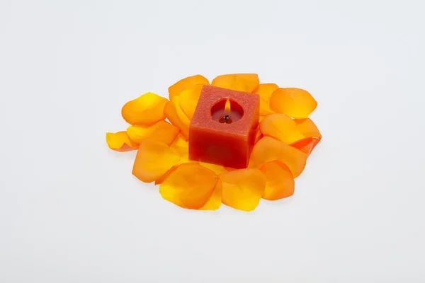 Spilt petals of the orange-rose around the aromatic candle — Stock Photo, Image