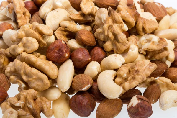 Bakgrund av blandade nötter - hasselnötter, valnötter, cashewnötter och pinjenötter — Stockfoto