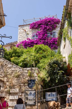 Eze, Fransa - 18 Haziran 2025: Eze 'deki ünlü, büyüleyici tünemiş köy çiçek açan kırmızı bougainvillea çiçekleri. Fransa 'nın Alpes-Maritimes bölgesinde çok popüler bir turizm merkezi..
