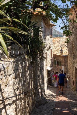 Eze, Fransa - 18 Haziran 2025: Eze 'nin dar sokaklarında yürüyen turistler - Fransa' nın Alpes-Maritimes bölgesindeki ünlü, büyüleyici tünemiş köy.