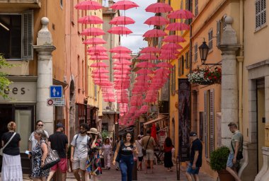 Grasse, Fransa - 17 Haziran 2025: Grasse sokakları, parfümerisiyle tanınan, geleneksel uluslararası gül fuarı vesilesiyle pembe şemsiyelerle süslenmiş bir şehir.