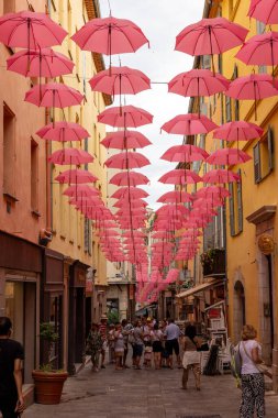 Grasse, Fransa - 17 Haziran 2025: Grasse sokakları, parfümerisiyle tanınan, geleneksel uluslararası gül fuarı vesilesiyle pembe şemsiyelerle süslenmiş bir şehir.