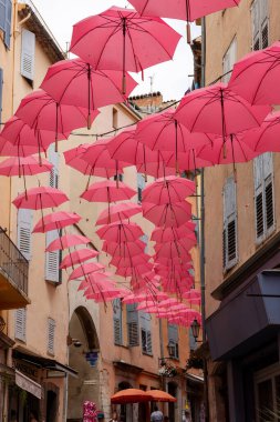 Grasse, Fransa - 17 Haziran 2025: Grasse sokakları, parfümerisiyle tanınan, geleneksel uluslararası gül fuarı vesilesiyle pembe şemsiyelerle süslenmiş bir şehir.