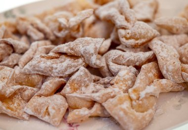 Melek kanatları (Faworki), kekler. Kızarmış tatlı ve üzerine pudra şekeri serpiştirilmiş.