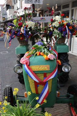 Noordwijkerhout, Hollanda - 21 Nisan 2023: Noordwijkerhout 'ta akşam aydınlatması yapılan Çiçeklerle süslenmiş traktör