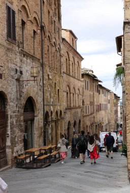 San Gimignano, İtalya - 17 Eylül 2022: Ortaçağ 'ın San Gimingnano kentindeki Via San Mateo' da turistler. Toskana, İtalya