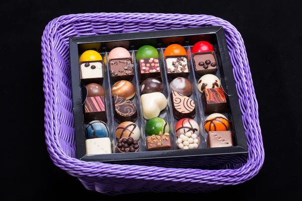 Набор различных шоколадных пралине в корзине лаванды — стоковое фото