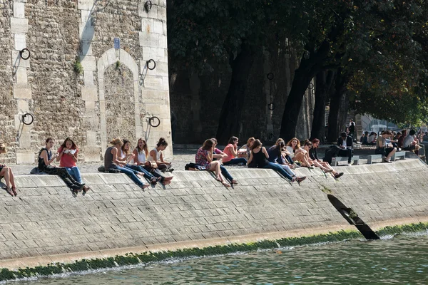 Parisiens et touristes pique-niquent et se détendent sur l'île de St Louis. Le quai de Seine est un endroit populaire pour le pique-nique et les promenades le week-end. Paris, France — Photo