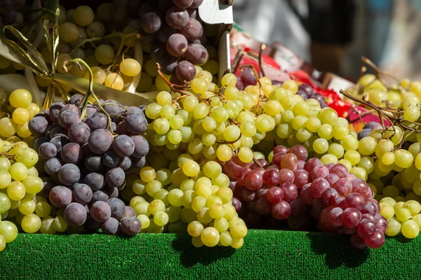 Bossen van rode en witte druiven op de boerenmarkt. — Stockfoto