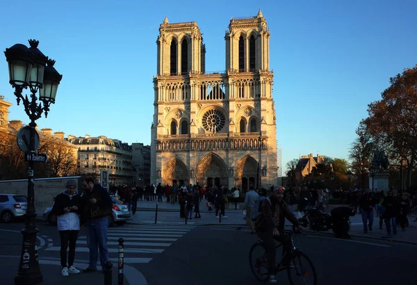 フランス 2018年11月18日 ノートルダム パリの夜間のフロントビュー黄色の太陽の光 日陰でそれの前に道路上の多くの人々 現実の都市生活 — ストック写真