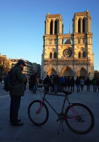 フランス 2018年11月18日 パリのノートルダム大聖堂の前の日陰で夜の黄色の太陽の下で自転車を持つ男 ストリートフォト — ストック写真