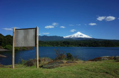 Villarrica volkanı ve Villarrica gölü manzaralı boş ahşap bilgi panosu. Şili doğası. Pucon