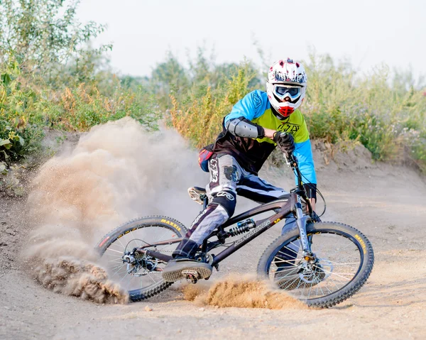 Ciclista de descenso profesional totalmente equipado que monta la bicicleta en el sendero polvoriento. Deportes extremos —  Fotos de Stock