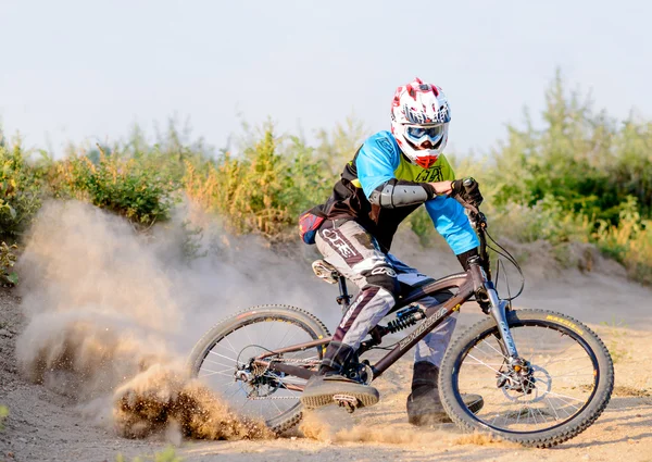 Ciclista de descenso profesional totalmente equipado que monta la bicicleta en el sendero polvoriento. Deportes extremos —  Fotos de Stock