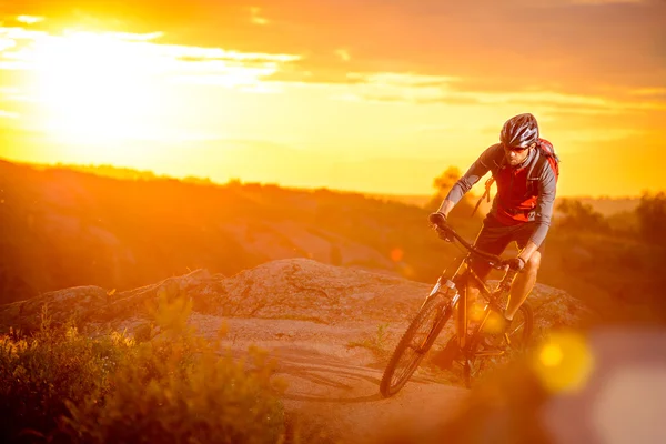 Ciclista montando en bicicleta por el sendero rocoso de montaña al atardecer —  Fotos de Stock