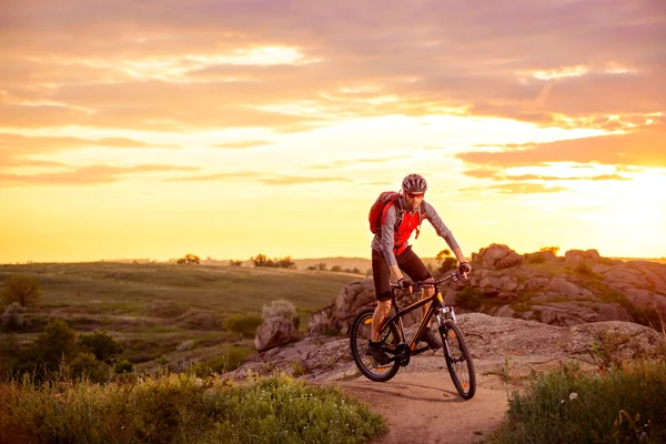 Cyklist ridning cykeln på berget steniga stigen vid solnedgången — Stockfoto