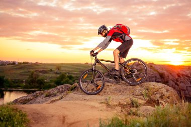 Cyclist Riding the Bike on the Mountain Rocky Trail at Sunset clipart