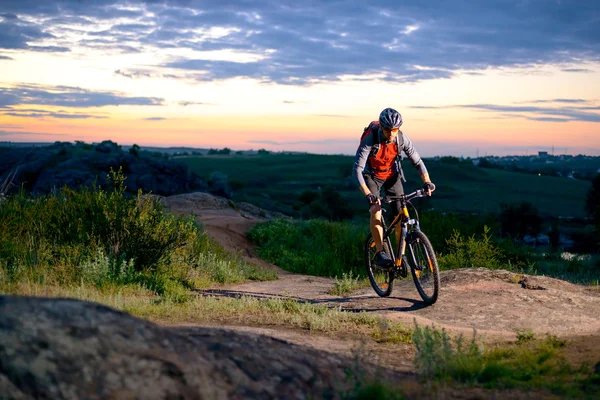 Ciclista montando a bicicleta na montanha Rocky Trail ao pôr do sol — Fotografia de Stock