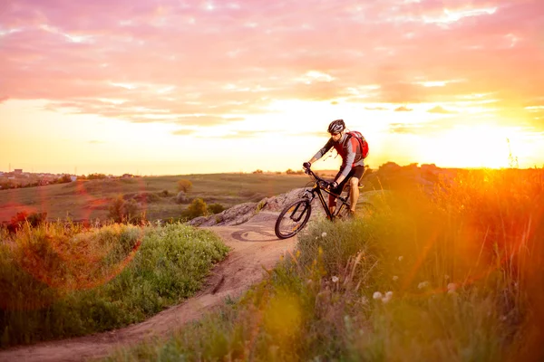 Ciclista in sella alla bicicletta sul sentiero roccioso di montagna al tramonto — Foto Stock