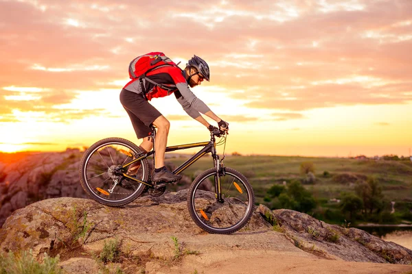 Ciclista in sella alla bicicletta sul sentiero roccioso di montagna al tramonto — Foto Stock