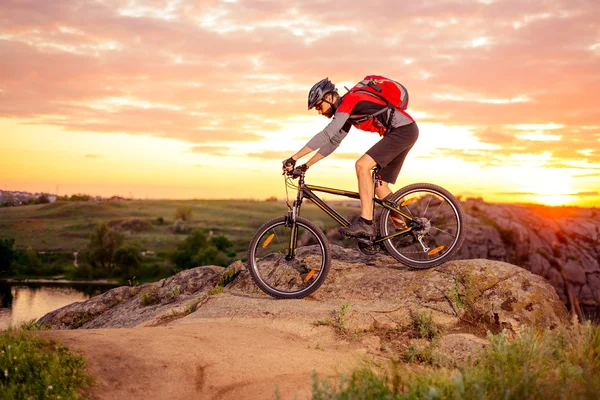 Cyklist ridning cykeln på Rocky skogsstig i solnedgången — Stockfoto