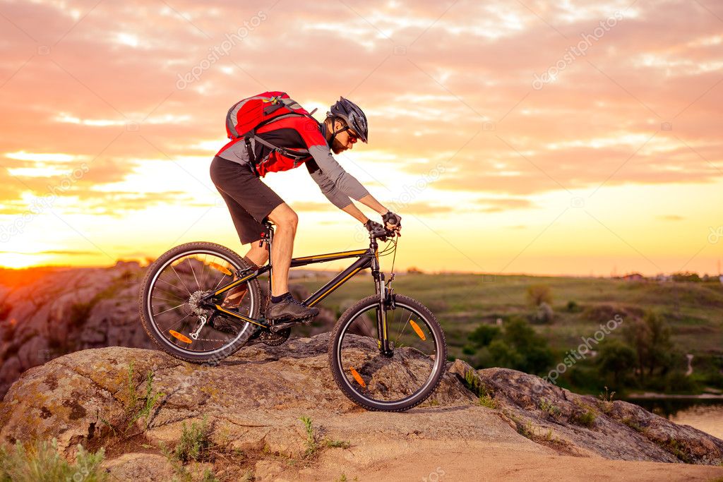 Cyclist Riding the Bike on the Mountain Rocky Trail at Sunset