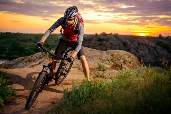 Ciclista montando a bicicleta na montanha Rocky Trail ao pôr do sol — Fotografia de Stock