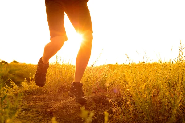 Γκρο πλαν των ποδιών του αθλητή που τρέχει στο βραχώδες βουνό ίχνος στο ηλιοβασίλεμα. Δραστήριο τρόπο ζωής — Φωτογραφία Αρχείου
