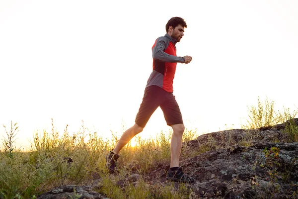 Joven deportista corriendo por el sendero de las Montañas Rocosas al atardecer. Estilo de vida activo —  Fotos de Stock