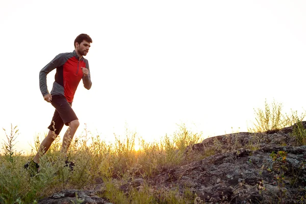 Jovem desportista a correr no Rocky Mountain Trail ao pôr-do-sol. Estilo de vida ativo — Fotografia de Stock