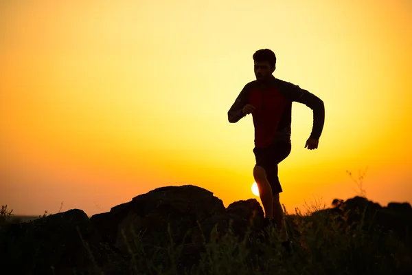 年轻的运动员在日落时分在岩石的山径上运行。积极的生活方式 — 图库照片