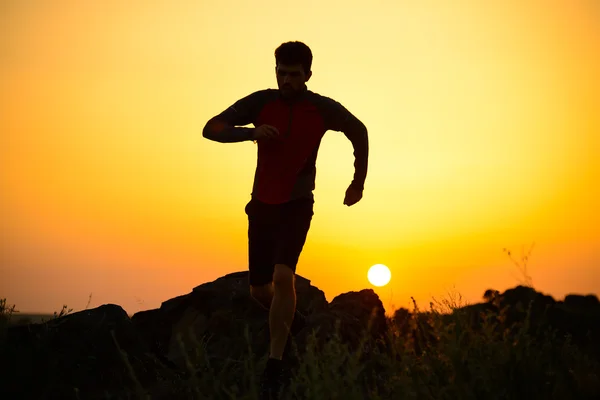 年轻的运动员在日落时分在岩石的山径上运行。积极的生活方式 — 图库照片