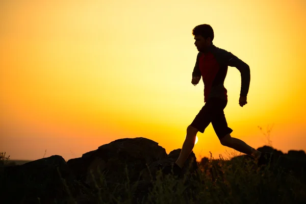 Joven deportista corriendo por el sendero de las Montañas Rocosas al atardecer. Estilo de vida activo —  Fotos de Stock