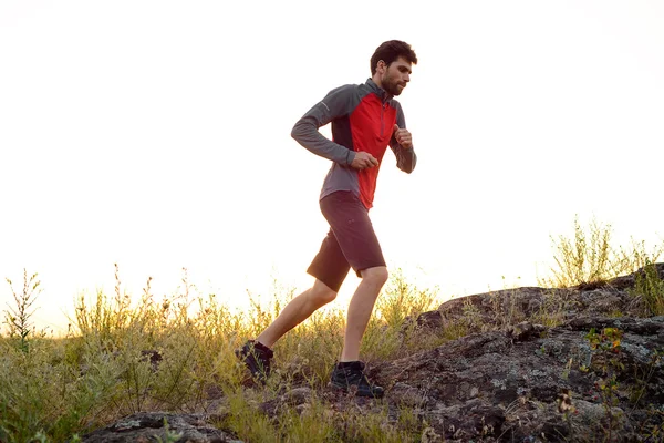 Joven deportista corriendo por el sendero de las Montañas Rocosas al atardecer. Estilo de vida activo —  Fotos de Stock