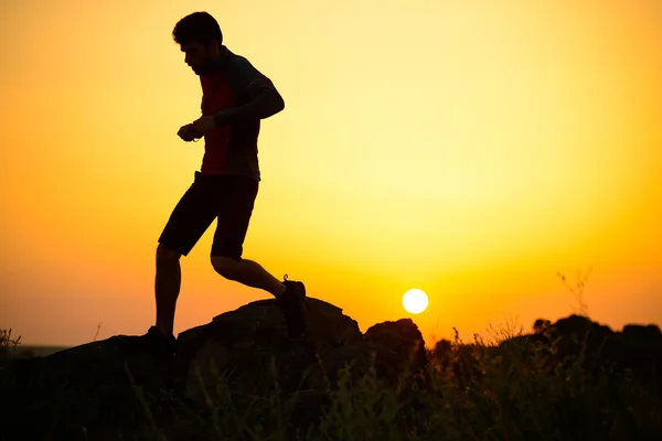 Joven deportista corriendo por el sendero de las Montañas Rocosas al atardecer. Estilo de vida activo — Foto de Stock