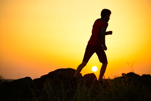 Νεαρός αθλητής τρέχει στο βραχώδες βουνό ίχνος στο ηλιοβασίλεμα. Δραστήριο τρόπο ζωής — Φωτογραφία Αρχείου