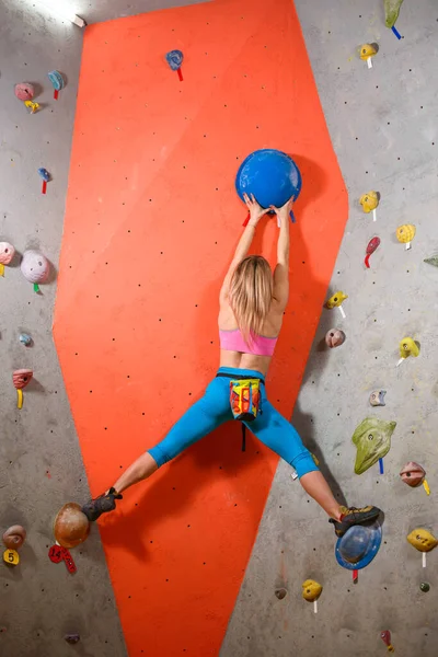 Mujer escaladora practicando escalada en roca en el Bouldering Gym. Deporte extremo y concepto de escalada interior —  Fotos de Stock