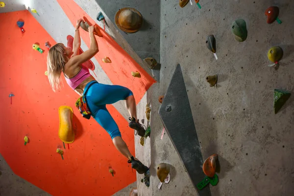 Mujer escaladora practicando escalada en roca en el Bouldering Gym. Deporte extremo y concepto de escalada interior —  Fotos de Stock