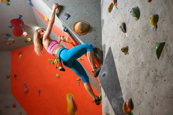 Mujer escaladora practicando escalada en roca en el Bouldering Gym. Deporte extremo y concepto de escalada interior —  Fotos de Stock