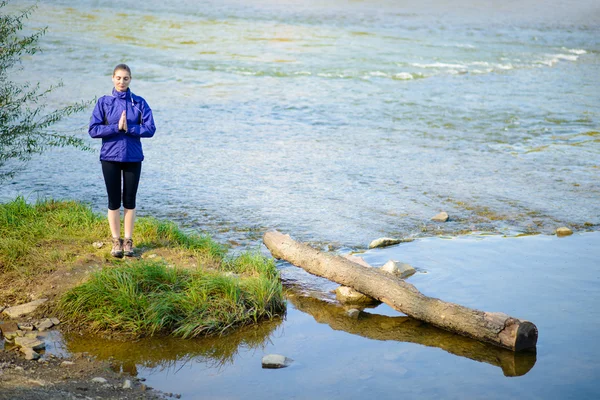 Ung smuk kvinde meditere på floden - Stock-foto