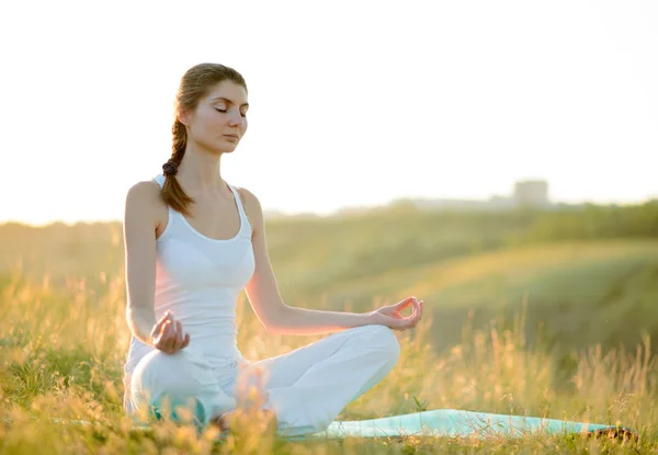 Jovem bela mulher pratica Yoga no prado ensolarado — Fotografia de Stock