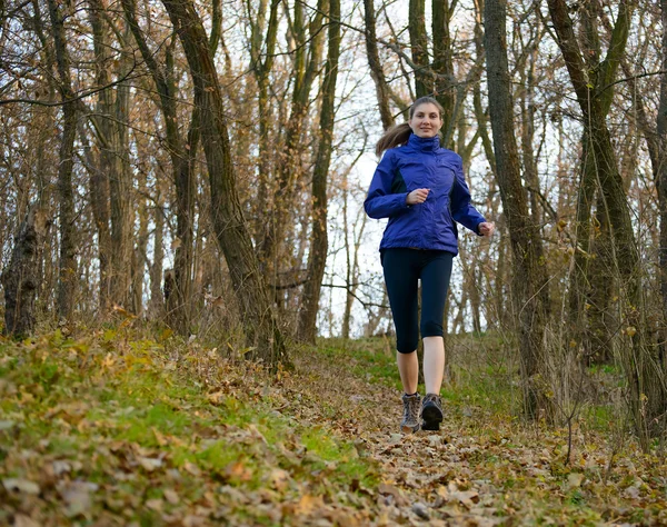 Joven mujer deportiva corriendo por el sendero en el bosque salvaje —  Fotos de Stock