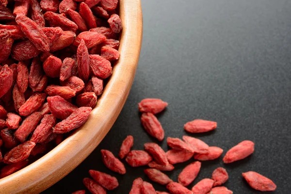 Wooden Bowl Full of Dried Goji Berries on the Black Table — Stock Photo, Image