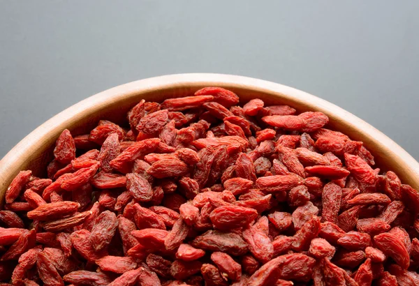 Tigela de madeira cheia de bagas secas Goji na mesa escura — Fotografia de Stock